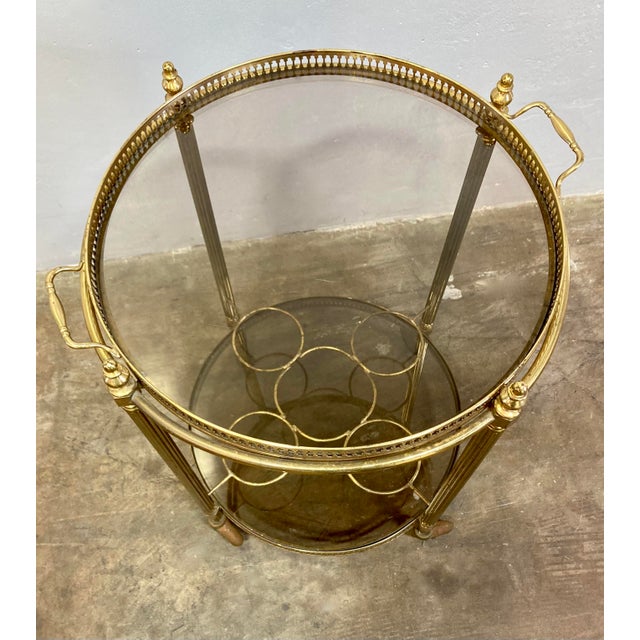 Authentic Hollywood Regency era rolling bar trolley. Likely manufactured by Maison Jansen in the 1940's. Brass frame and...