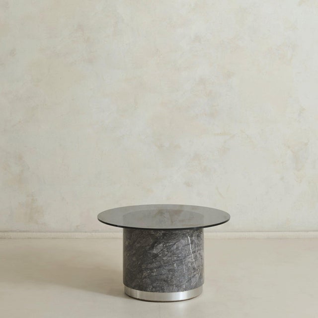 A sculptural Italian coffee table from the 1970s. The round smoked glass top, measuring 26 inches in diameter, rests on a...