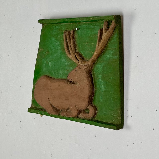 A gorgeous Folk Art primitive piece depicting a resting stag (male deer) placed inside an avocado-green painted plaque. We...