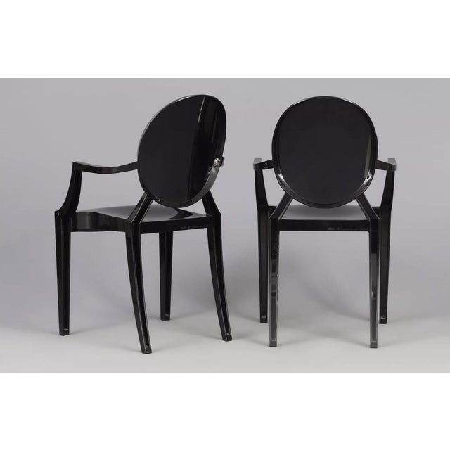 Elegant kartell louis ghost armchairs, designed by philippe starck. Made of black, translucent plastic, these chairs bring...