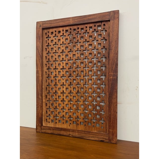 This decorative wooden lattice panel features a repeating geometric open work pattern set within a solid rectangular wood...