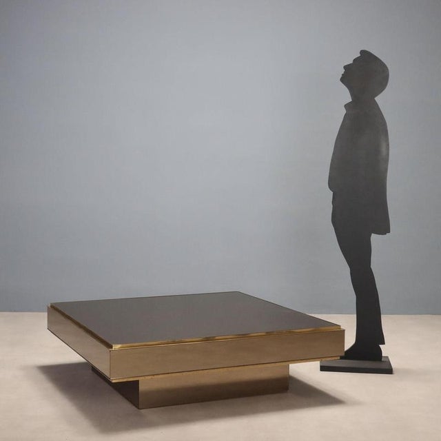 This 1980s-era wooden coffee table with smoked glass covering is an example of the elegant and functional design typical...