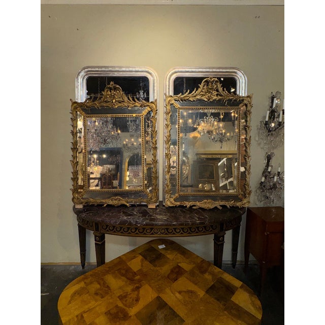 The product is a set of two 19th century French gilded cushion mirrors. These elegant mirrors feature intricate gilded...