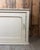 This vintage low cabinet is distinguished by its elongated shape, molded panels, and original off-white patina. Its...