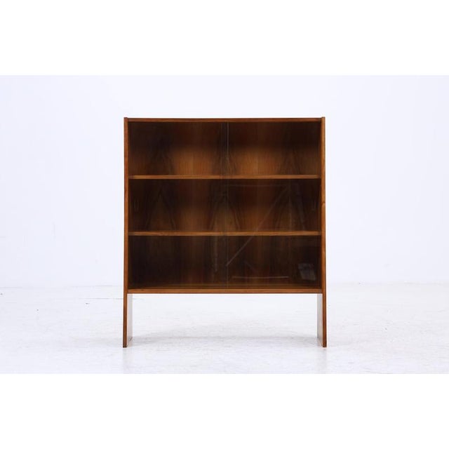 Beautiful mid-century bookcase with glass sliding doors Timeless design • Material: Walnut, glass • 2 shelves • 2 glass...