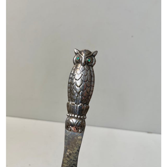 Gem set letter opener in partially hammered high-quality silver plate. The handle shaped as an owl with green gem stone...