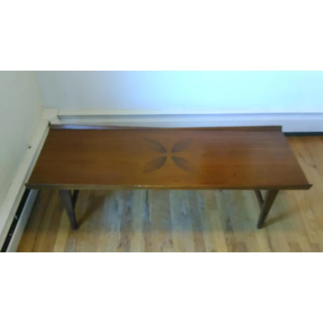 Unique and beautiful walnut coffee table with raised angled edges and rosewood leaf inlays in the center. Stamped by Lane...