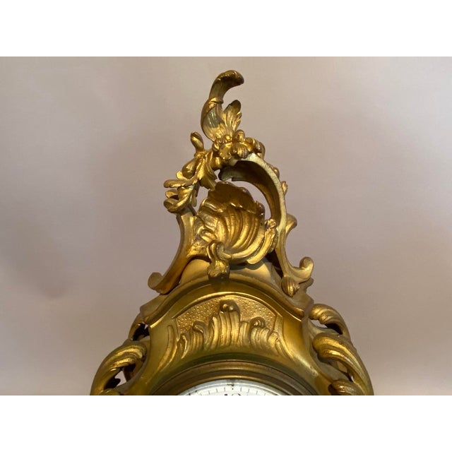 A refined 19th-century French Louis XV-style mantel clock, crafted in richly detailed ormolu bronze and fitted with a...