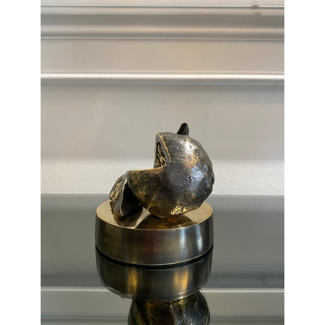 A contemporary still-life bronze of a fig, opened to reveal its seeded interior, with a single segment resting at its side...