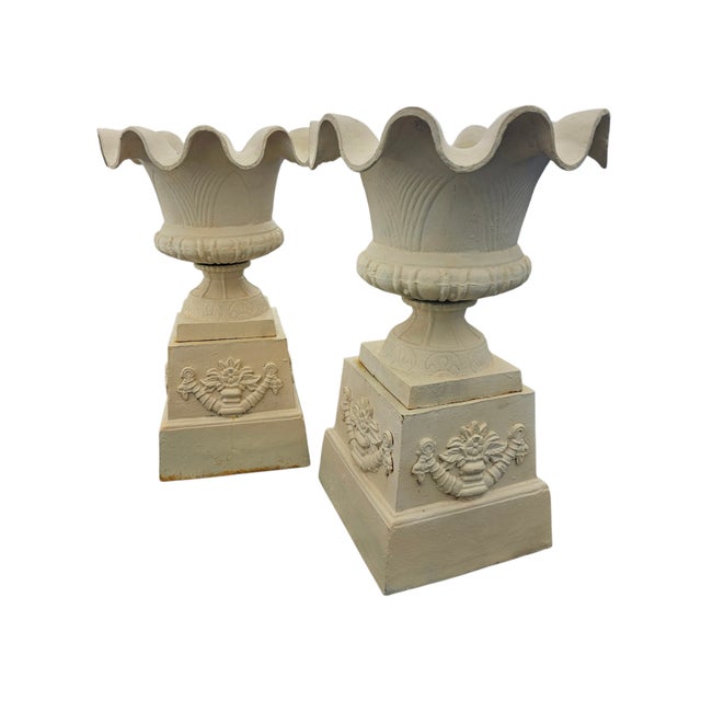 This pair of garden urns is in neoclassical style, with ruffled edge sitting on matching cast iron, painted pedestals....