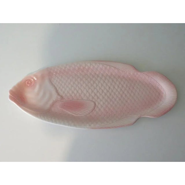 Large serving dish in pink glazed ceramic with salmon motif in relief. The dish was made in France at Salins les Bains...