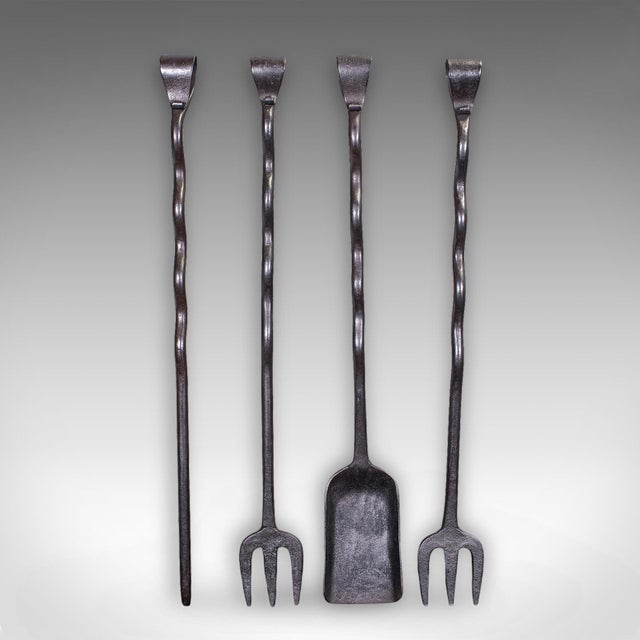 This is a set of four antique country house inglenook fire tools. An English, blacksmith forged iron companion set, dating...