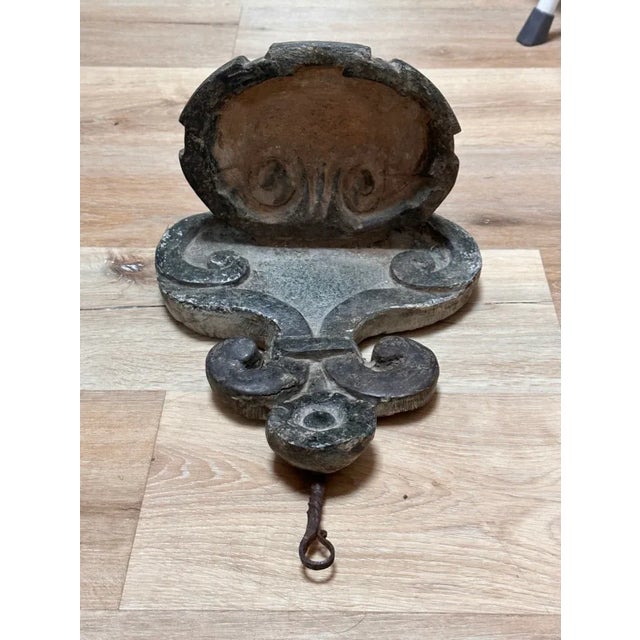 Exceptional grey marble/stone hanging font with carved shield form back supporting a shell-form font, having wrought iron...