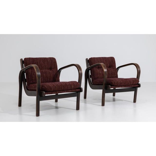 A pair of mid-century armchairs attributed to Kozelka, featuring bentwood frames combined with upholstered seating. The...