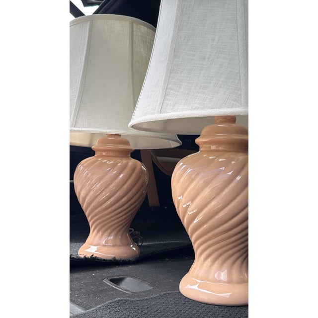 Charming vintage pair of table lamps featuring beautifully sculpted blush pink ceramic bases with an elegant spiral,...