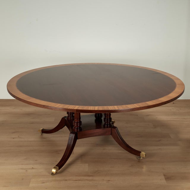 Impressive large dining table crafted in mahogany in classic regency style, having a round top with satin wood cross...