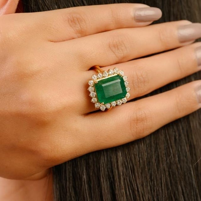 This luxurious Princess Diana inspired ring showcases a stunning emerald-cut emerald weighing 7.22 carats, artfully set in...