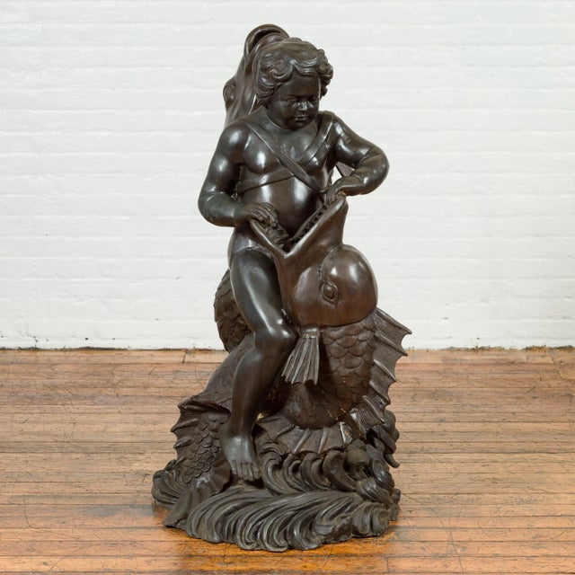 A Greco-Roman inspired vintage bronze fountain from the mid 20th century, depicting a putto riding a dolphin. Created with...