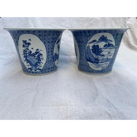 A matching pair of Chinese export porcelain cachepot or pots featuring traditional decoration including landscape scenes...