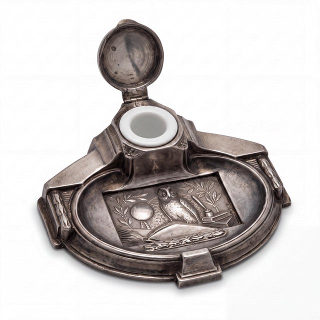 This is a 1930s French Art Deco style silvered spelter desk inkwell with wise owl motif. It has the original porcelain...