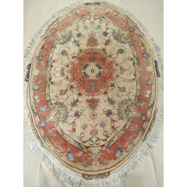 "A rare and exquisite vintage oval-shaped Persian Tabriz area rug from the late 19th century, featuring a delicate floral...