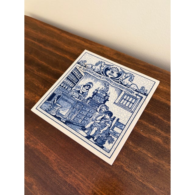 A classic Dutch Delft-style hand painted blue and white porcelain tile featuring a scene of women pharmacists in rich...
