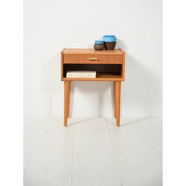 Scandinavian oak bedside table from the 1950s and 1960s with open compartment and drawer, featuring a brass handle and...