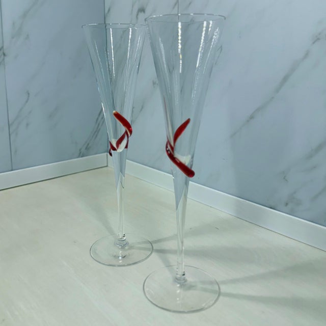 Two hand‑blown champagne flutes issued for G.H. Mumm’s “Cordon Rouge” promotion in the 1980s. Clear bowls are wrapped with...