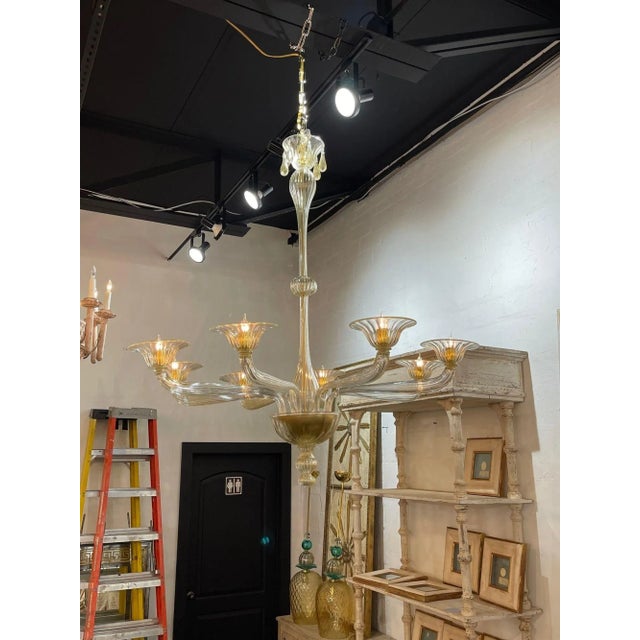 Stylish modern Murano glass chandelier with 8 lights. Featuring beautiful glistening gold glass and decorative arms and...