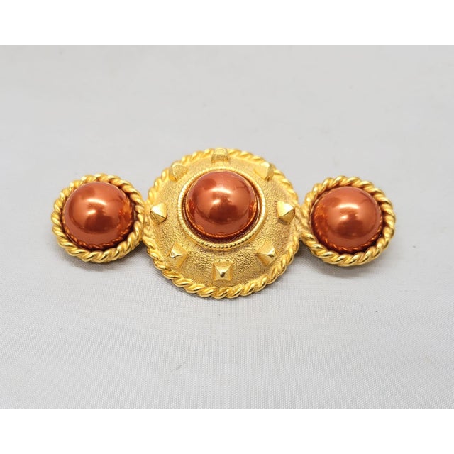 1990s goldtone faux-red pearl center surrounded by studs with two round pearls with goldtone rope design around them on...