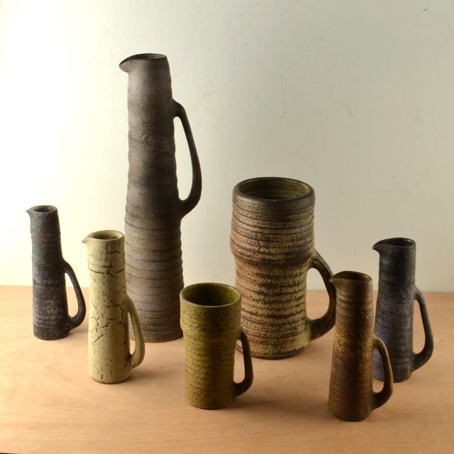 Rare group of seven whimsical jugs / vases with long downward ears in various heights with earth tone glazes. They are...