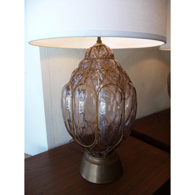 This is a pair of large mid century glass table lamps. They're made from a dusty rose colored glass with brass accents on...