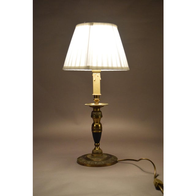 A refined vintage brass table lamp with an elegant candlestick silhouette, accented by a deep green decorative detail and...