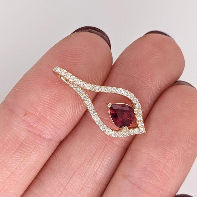 A Mozambique ruby glows with red brilliance at the heart of this pear pendant, framed by a trail of brilliant natural...