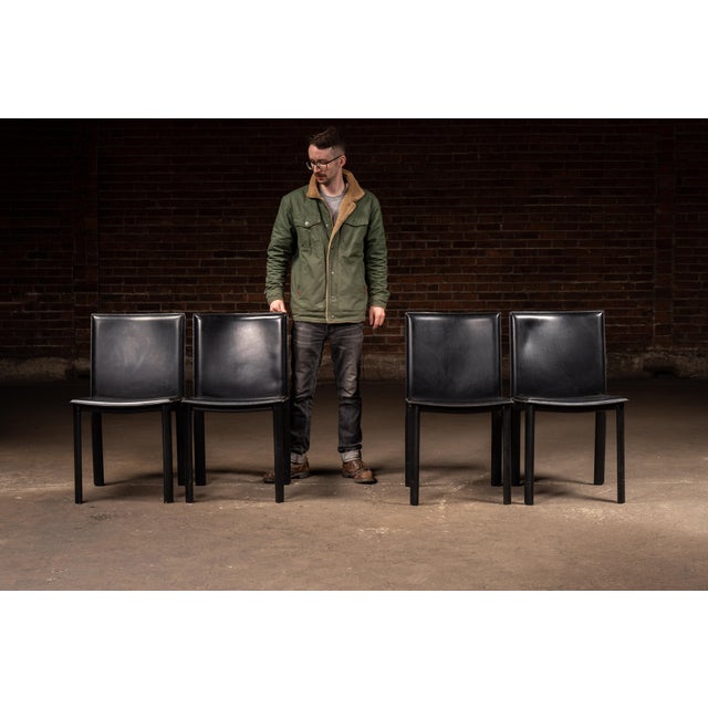 Set of four minimalist late 20th-century Postmodern dining chairs executed in black leather over streamlined tubular...