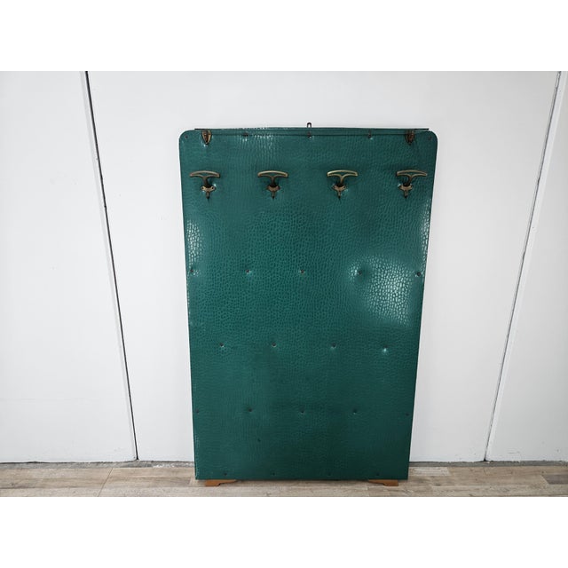 Vintage 1950s wooden coat rack covered in green vinyl and decorated with brass hooks. The top features an original clear...