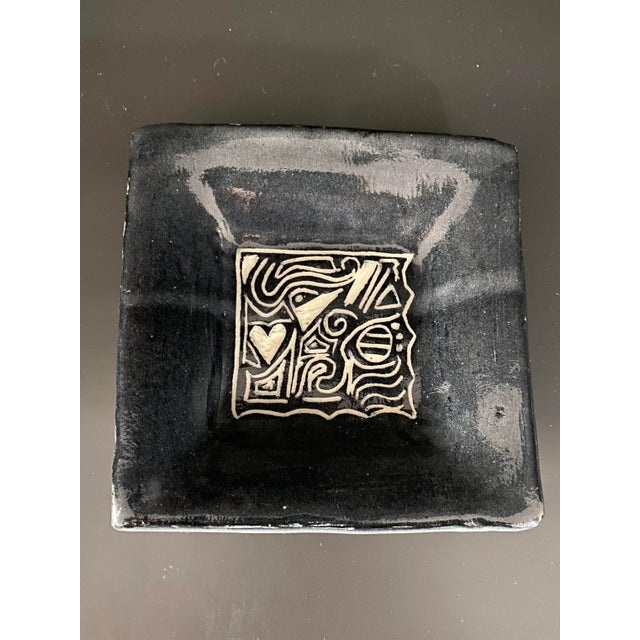 Super cute postmodern glazed ceramic studio pottery dish. In a deep, deep grey, almost black background. Design and...