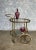 A handsome French bar cart from the 1940s having a brass frame and 2 oval shaped glass shelves enclosed in a brass...