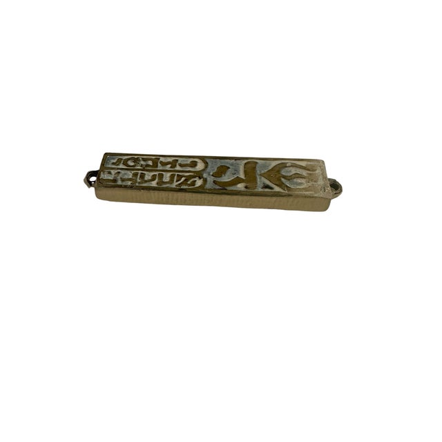 Vintage metal mezuzah case used to contain a parchment scroll. It features decorative Hebrew lettering. The top letter...