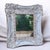 This French Country wall mirror features a heavily distressed white frame with gold trim. Ornate wooden with cutouts details.