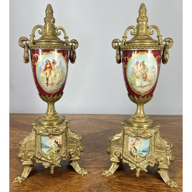Crafted in richly detailed gilt brass, the central clock is complemented by two matching urns, each adorned with hand-...