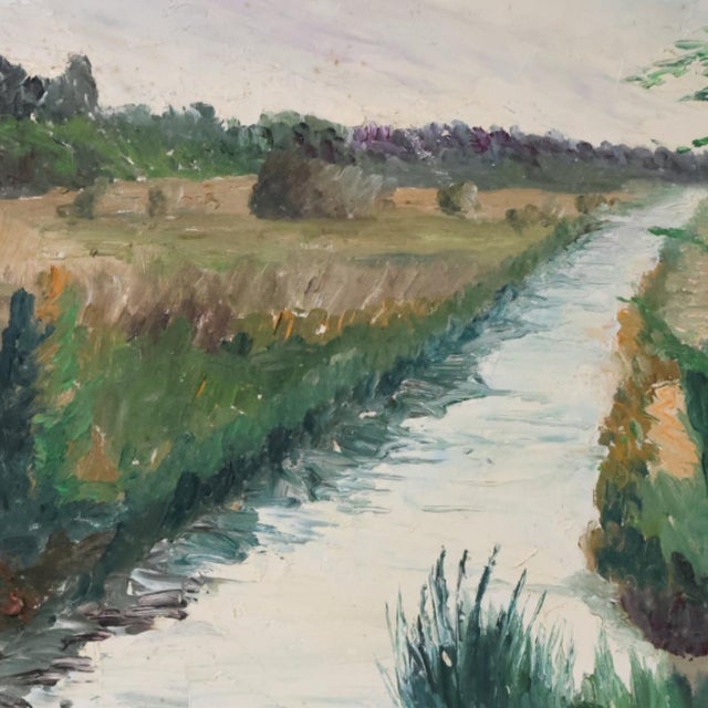 This mid-20th century French riverside painting captures the peaceful charm of a riverbank scene, where water gently meets...