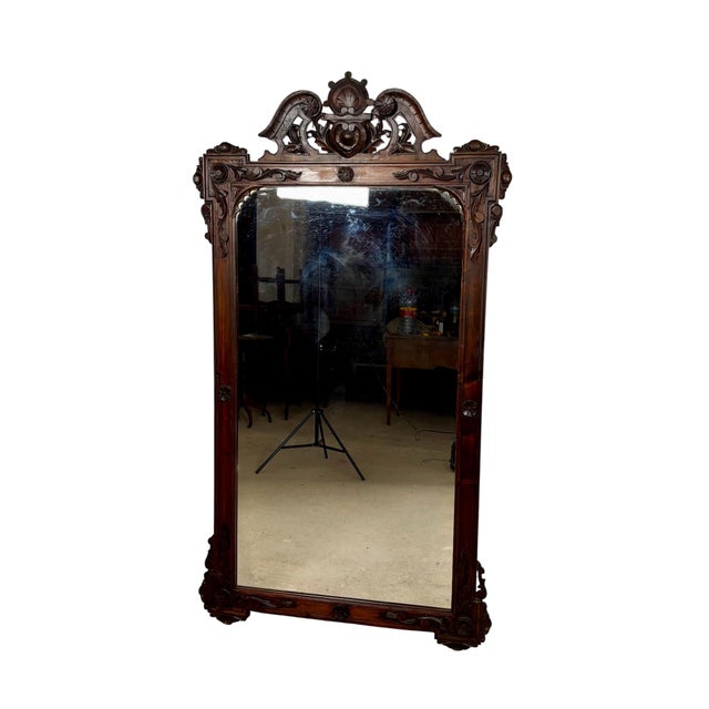 Large antique wall mirror featuring an elaborately hand-carved frame with exceptional decorative detailing. The mirror is...