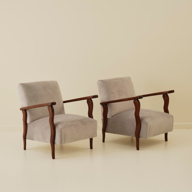 Pair of armchairs by an Italian manufacturer, circa 1940. Featuring sculpted wood frames and rich velvet upholstery, the...