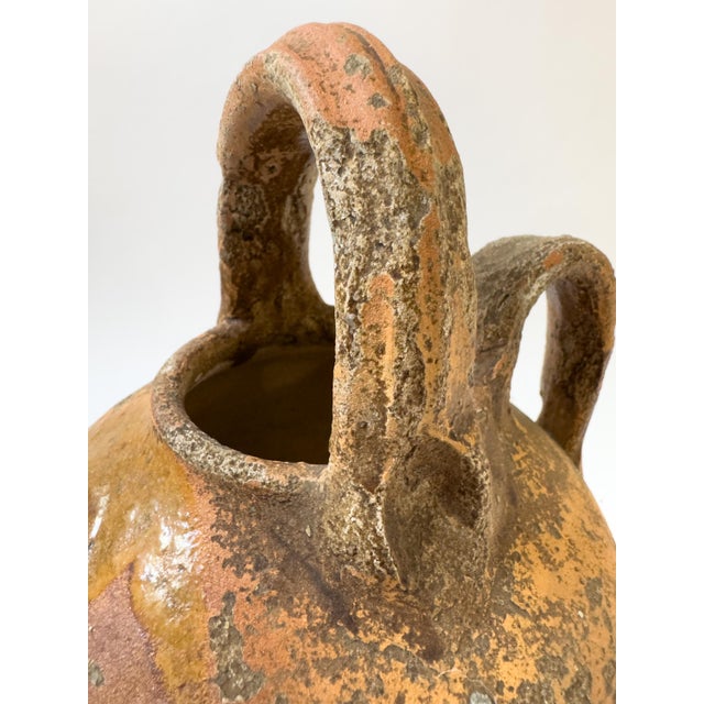 A charming antique French terracotta cruche, featuring a rounded body, short pouring spout, two arched handles and a...