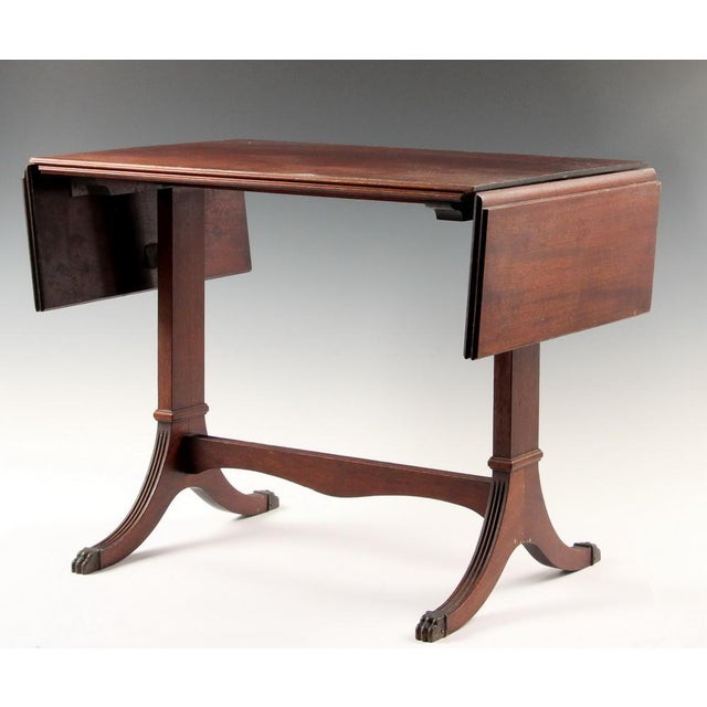 A 1930s Duncan Phyfe style mahogany side table with drop leaves, trestle legs and stretcher and brass toe caps Product...
