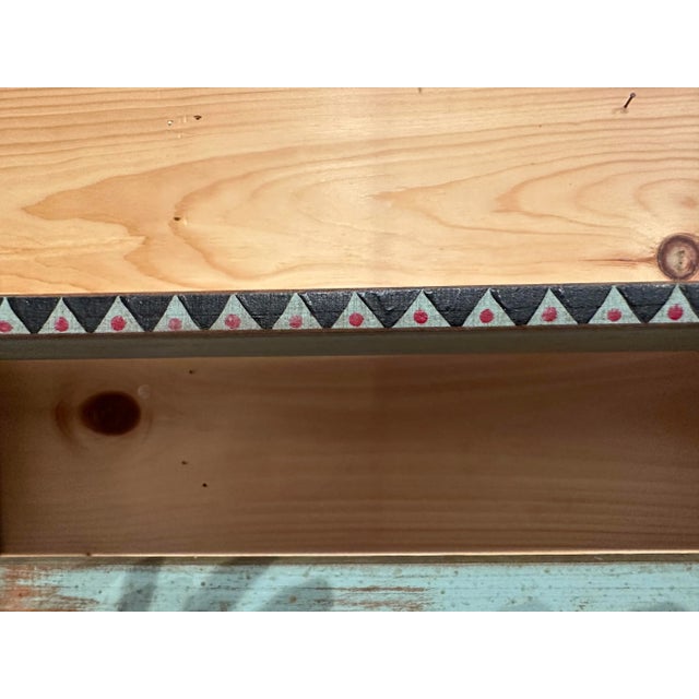 Pale blue painted shelf with triangle painted pattern along shelf edge in blur blue and raspberry red dot. Made from maple...