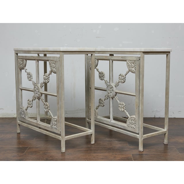 A pair of 19th-century French consoles combining a painted iron frame with inset carved wood panels, all unified under a...