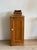 Honeyed English pine with a single paneled door and a small white porcelain knob. A low cabinet form with a recessed panel...