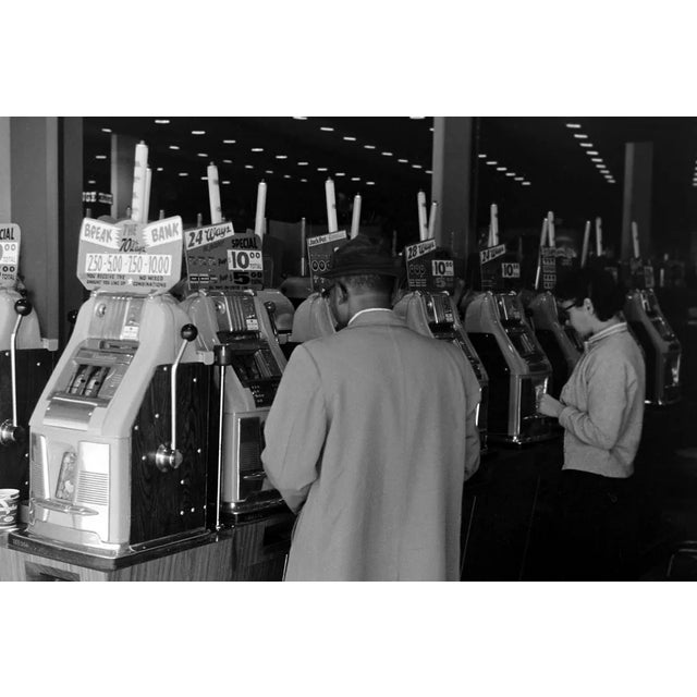 The black-and-white photograph titled Visiting Las Vegas, 1962 offers a snapshot of the vibrant atmosphere in a casino...